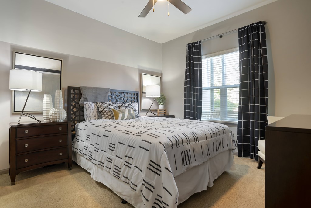 A bedroom with a bed, dresser, and ceiling fan.